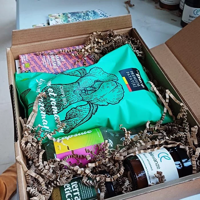 Geopende geschenkdoos met ambachtelijke producten: een OALI-kaars, bio-chips, chocolade en limonade